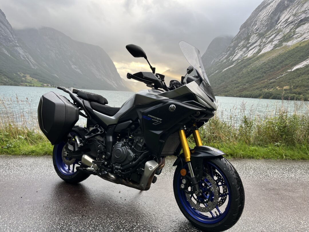 Sport motorcycle parked by a misty lake with towering mountains in the background.